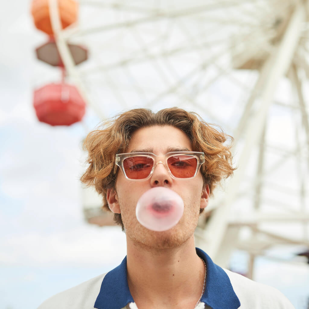 Guy blowing a bubble gum and wearing noel red