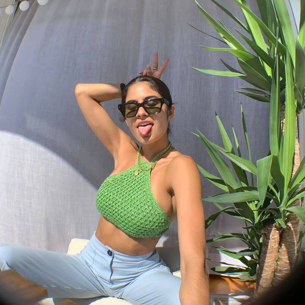 Girl doing a gesture with her tongue out in a green top wearing remi